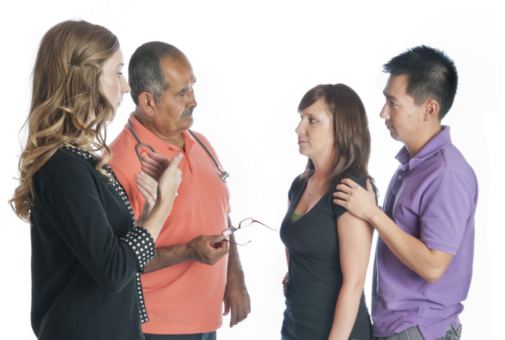 a sign language interpreter facilitates conversation with a patient and her husband